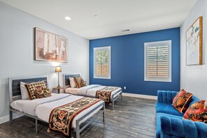 Ein Schlafzimmer mit zwei Betten, einem blauen Sofa und Bildern an den Wänden.