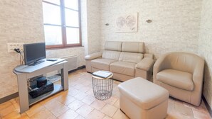 Ein modernes Wohnzimmer mit Sofa, Sessel und Fernseher auf einem Schrank.