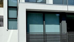 A modern two-story building with large windows and a balcony.