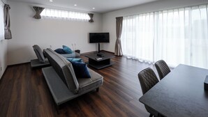A modern living room with a sofa, TV, and dining table.