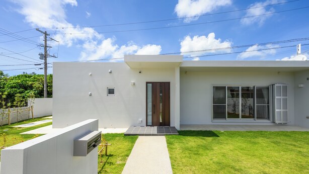 A modern two-story house with a white exterior, a front door, and a small front yard.