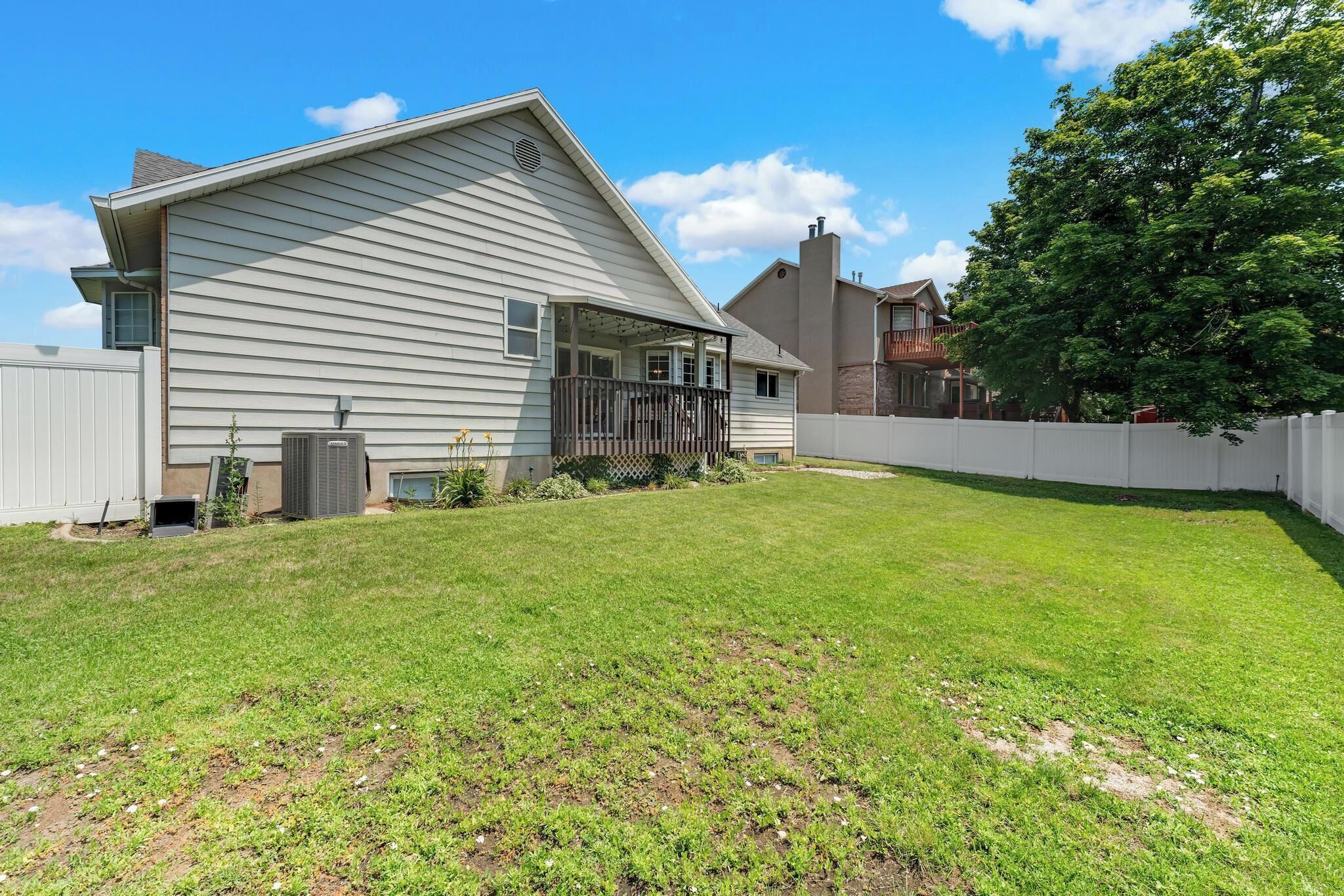 A residential house with a sloped roof, a covered porch, and a fenced backyard.