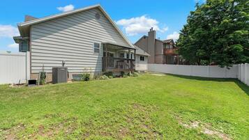 A residential house with a sloped roof, a covered porch, and a fenced backyard.