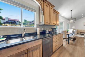 Una cocina moderna con armarios de madera, un lavamanos de acero inoxidable y un lavavajillas.