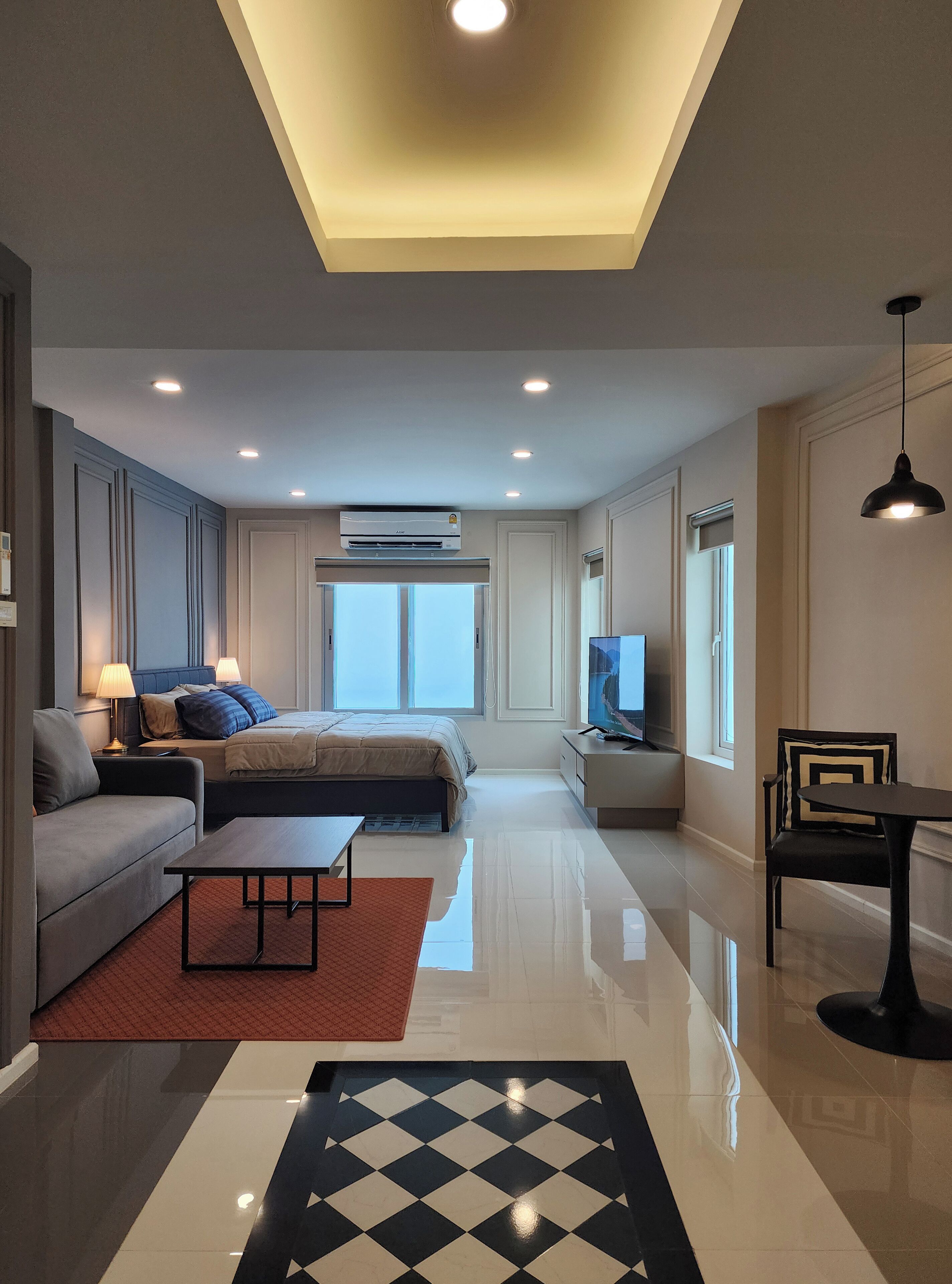 A modern hotel room with a large bed, a sofa, a TV, and a dining area. - Nice Decorated townhouse in local neighborhood, 10 minutes walk to BTS (Thunburi)