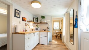 Una cocina compacta con armarios blancos, una encimera de madera y un microondas integrado.