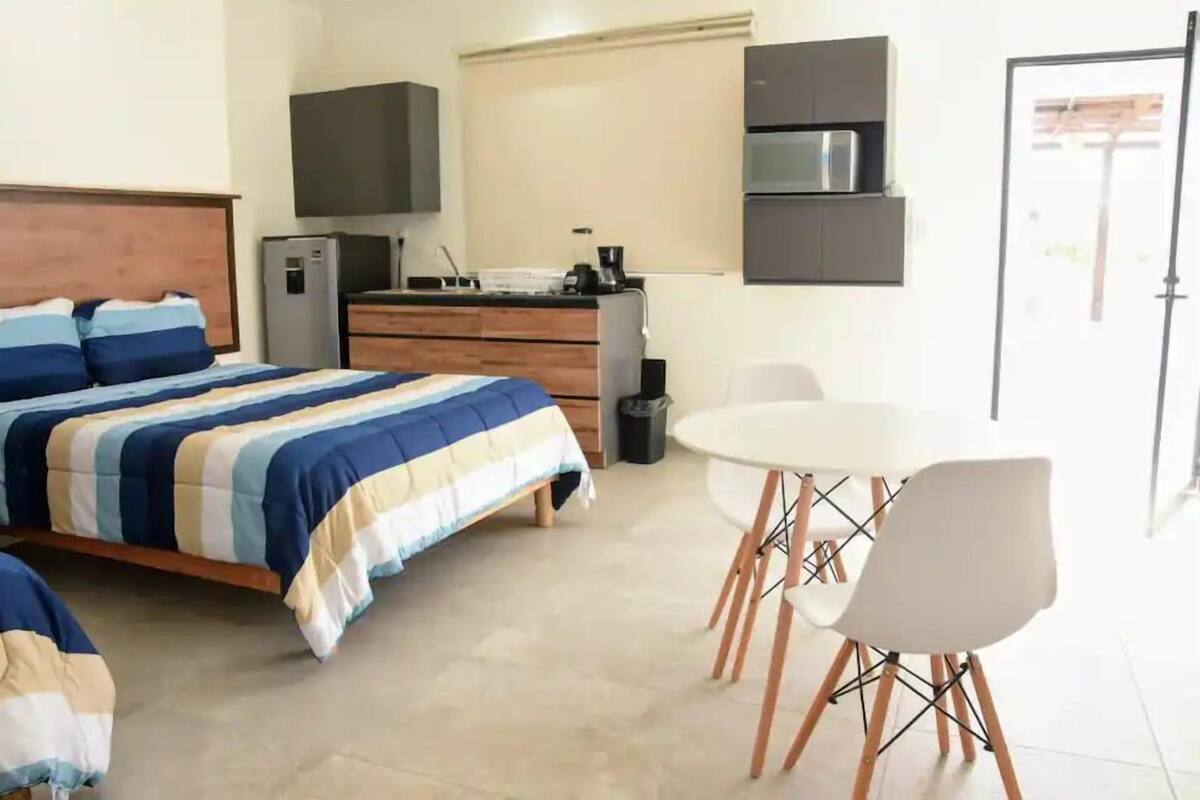 Un dormitorio con cama, escritorio, silla, televisor y microondas.