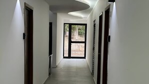 A hallway with a modern design, featuring a curved ceiling and a view through a glass door at the end. - MARAZUL-HOME (Playa del Carmen)