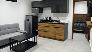 A compact living space with a kitchenette, a sofa, a coffee table, and a bed. - MARAZUL-HOME (Playa del Carmen)