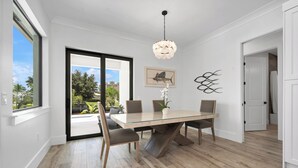A modern dining area with a glass table, wooden chairs, a chandelier, and a view of the outdoors. - Amazing apartment with AC in Bacolod (Bacolod)