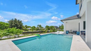 A rectangular swimming pool with clear blue water, surrounded by a tiled deck. There are lounge chairs and a small table near the pool's edge. - Amazing apartment with AC in Bacolod (Bacolod)