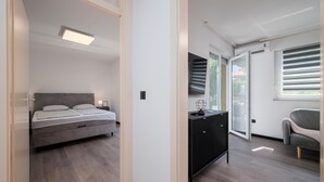 A modern bedroom with a bed, bedside table, and a view of the outdoors through a sliding door. - 1 bedroom beautiful apartment in Vranici (Vranici)