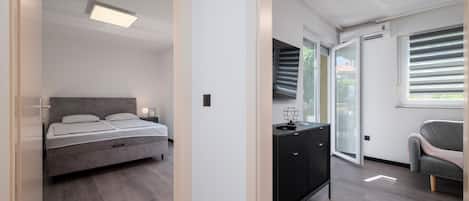 A modern bedroom with a bed, bedside table, and a view of the outdoors through a sliding door.