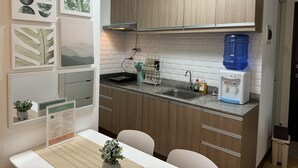 A compact kitchen with wooden cabinets, a built-in stove, a water dispenser, and a sink. - Cozy & Quiet 1 BR Condo w/ Free Pool Access Near Beach, Airport and Malls (Davao City)