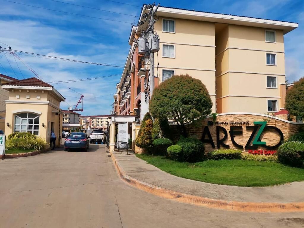 A residential building with a sign reading "AREZ Properties" and a well-maintained lawn.