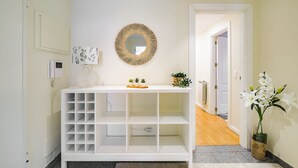 Une console blanche avec un miroir, une petite plante et un objet décoratif.