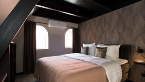 Un dormitorio con cama, ventana, equipo de aire acondicionado y pared con diseño.