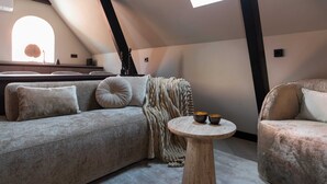 Un dormitorio tipo loft acogedor con un ventanal grande, un sofá, una mesa de centro redonda y una silla.