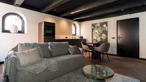 A modern living room with a grey sofa, a round coffee table, and a dining area with chairs and a table. - De Vooruitgang Sneek - de Zwette (Sneek)