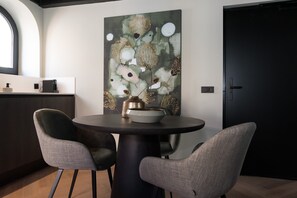 A dining area with a round table, two chairs, a coffee machine, and a large abstract painting on the wall. - De Vooruitgang Sneek - de Zwette (Sneek)