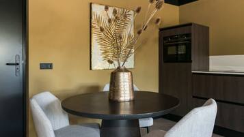 Uma área de refeições com uma mesa redonda, duas cadeiras, um vaso decorativo e um quadro pendurado na parede.