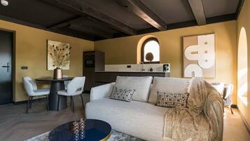 A modern living room with a sofa, a coffee table, and a dining area with chairs.