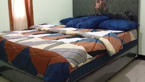 A bed with a striped quilt, a grey upholstered headboard, and a window with curtains. - Dhea Homestay Bromo (Ngadisari)
