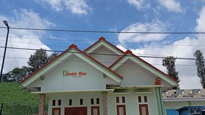 A two-story building with a green and red facade, a sign reading "Rondok Dhea," and a tiled entrance area. - Dhea Homestay Bromo (Ngadisari)