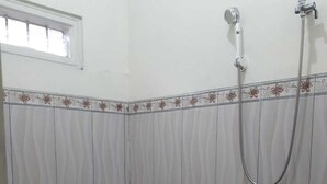 A small bathroom with a toilet, a shower, and patterned tiles. - Dhea Homestay Bromo (Ngadisari)