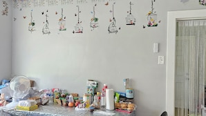 A room with a ceiling fan, a table covered with a plastic sheet, and various items on the table.