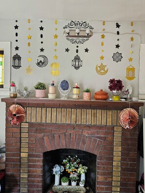 A fireplace with a brick mantel, decorated with potted plants and various decorative items. - Peaceful Private Room for Solo trip near Forest Park/U.City/Delmar Loop/Pagedale (St. Louis)