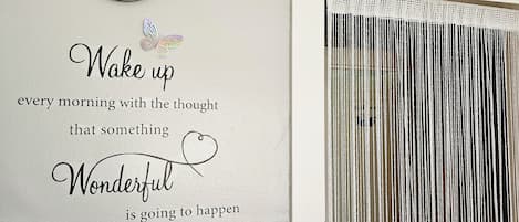 A wall with a clock, a decorative quote, and a birdhouse with butterflies.