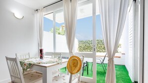 A room with a dining table, two chairs, and a view of a green lawn through large windows.