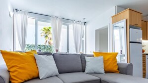 A modern living room with a grey sofa, yellow and white cushions, a white coffee table, and a book.
