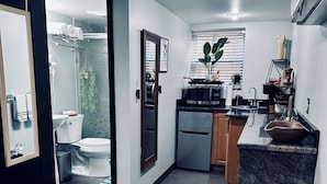A modern kitchen with a built-in oven, microwave, and sink. There is a wooden bench and a potted plant.