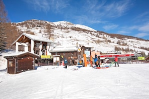 A ski resort with a wooden lodge, ski rental area, and a mountain backdrop.