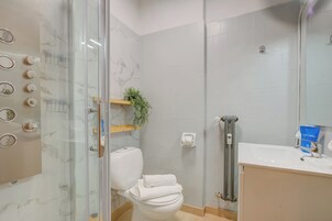 Un bagno moderno con box doccia in vetro, un WC, un lavandino e uno specchio.