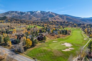 A golf course with a clear view of the surrounding mountainous landscape and residential area.