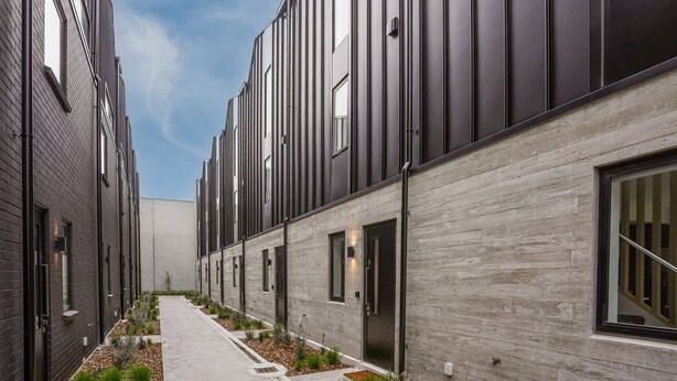 A modern building with a narrow walkway, large windows, and a mix of dark and light materials. - Central City Abode on St Asaph (Christchurch)