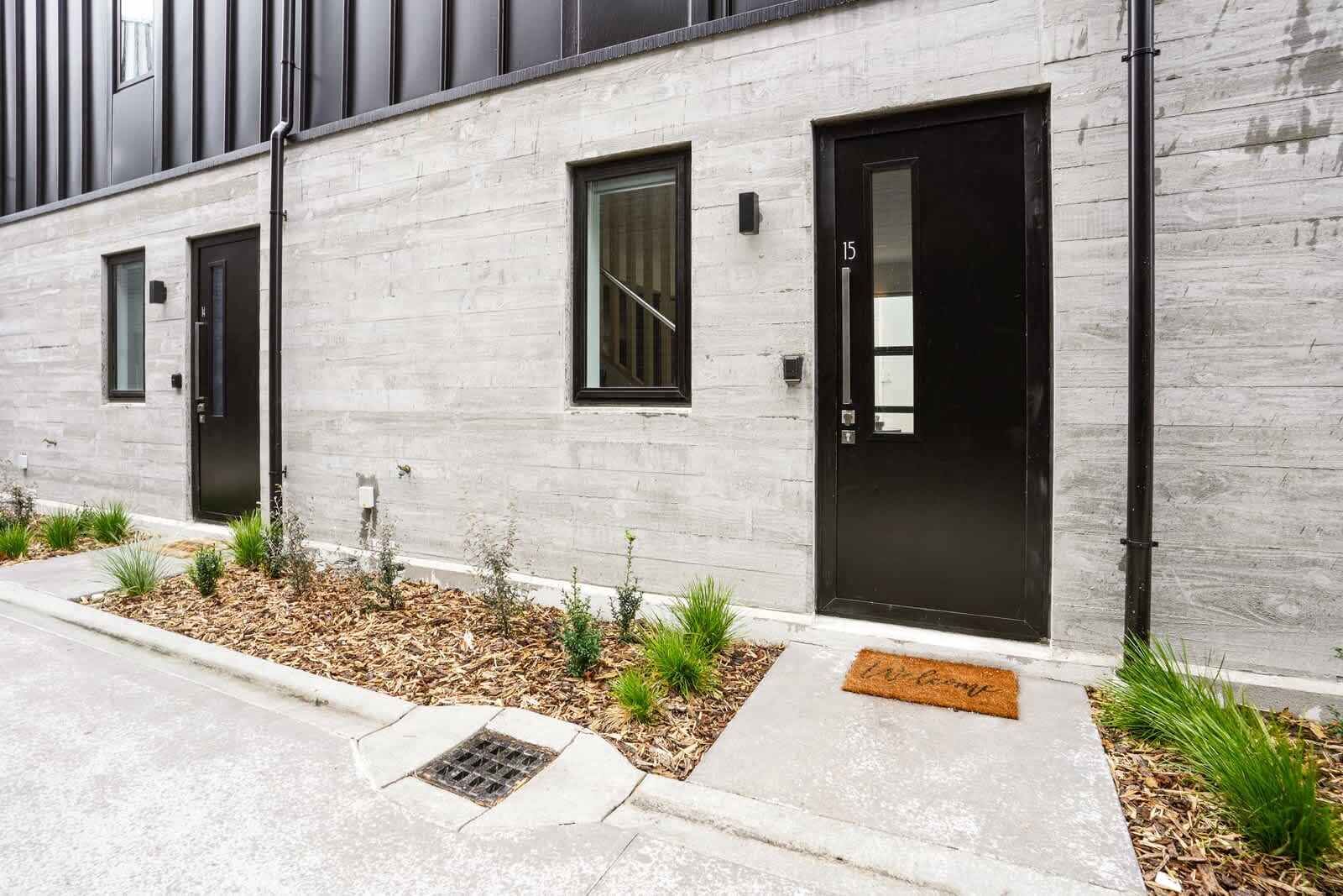 Un edificio moderno con fachada gris, puertas negras y ventanas pequeñas.