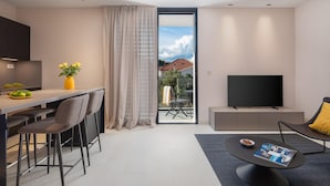 A modern living room with a flat-screen TV, a dining area with a table and chairs, and a large window with curtains. - Gorgeous apartment in Betina with WiFi (Betina)