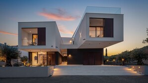 A modern two-story house with a unique V-shaped design, large windows, and a staircase leading to the entrance. - Gorgeous apartment in Betina with WiFi (Betina)
