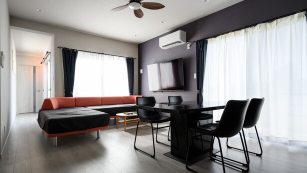 Ein modernes Wohnzimmer mit einer Couch, einem Esstisch, Stühlen und einem Deckenventilator.