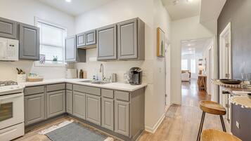 A modern kitchen with grey cabinets, a white countertop, and a wooden floor.