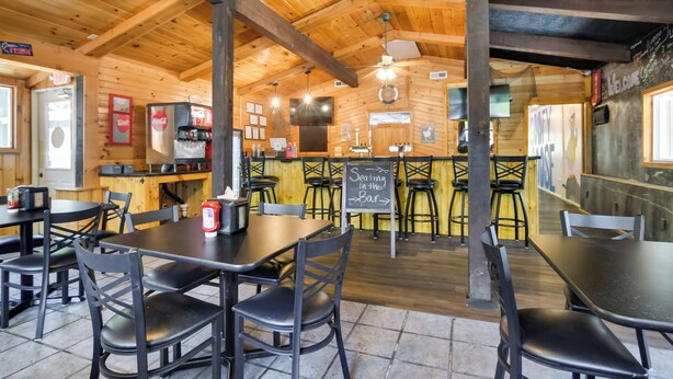 A restaurant with wooden interiors, tables and chairs, a bar area, and a chalkboard menu. - Table Rock Lake Apt w/ Community Dock & Fire Pits! (Kimberling City)