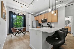 Una cocina moderna con una isla central, armarios de madera, electrodomésticos de acero inoxidable e iluminación colgante.