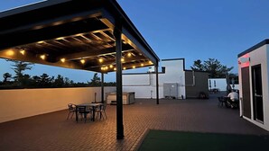 An outdoor patio area with a covered seating area, a barbecue grill, and a pool table. - Hot Tubs I 2 King BR I Condo I Near DT TC (Traverse City)