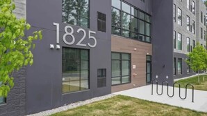 A modern building with the number 1825 on its facade, large windows, and a grassy area in front. - Hot Tubs I 2 King BR I Condo I Near DT TC (Traverse City)