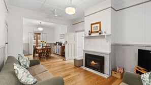 A living room with a fireplace, a dining area, and a kitchen. - Maison Cottage in Queenscliff (Queenscliff)