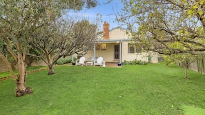 A house with a well-maintained lawn, a patio with outdoor furniture, and a brick chimney. - Maison Cottage in Queenscliff (Queenscliff)